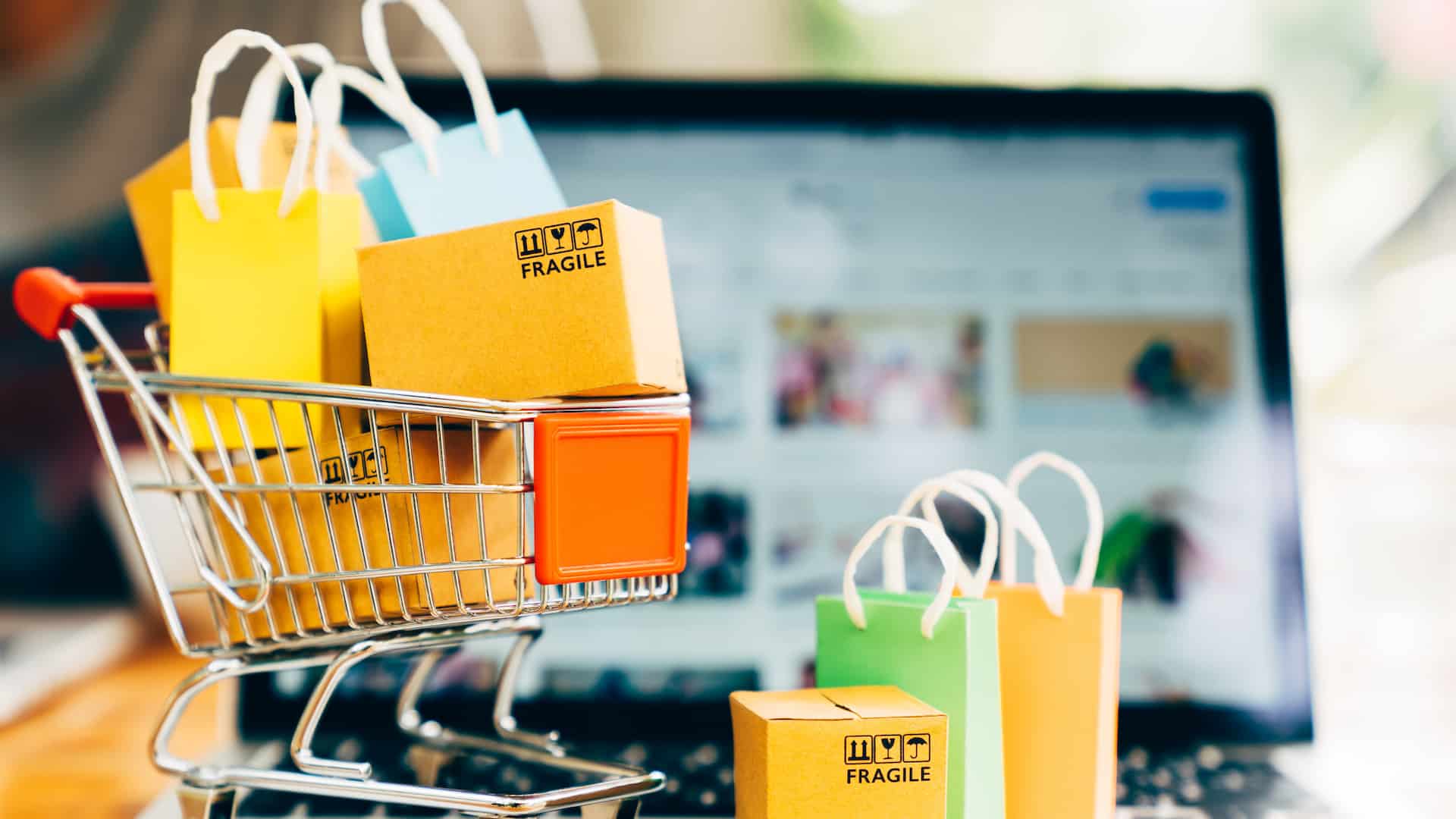 Product package boxes and shopping bag in cart with laptop computer which web store shop on screen for online shopping and delivery concept