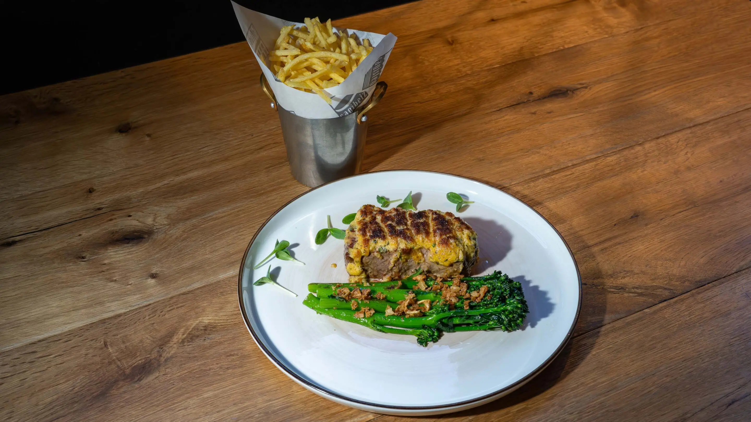 Eine kleine Gruppe fährt auf ihren Mountainbikes über einen Kiesweg, im Hintergrund ein blauer See und ein Schloss.